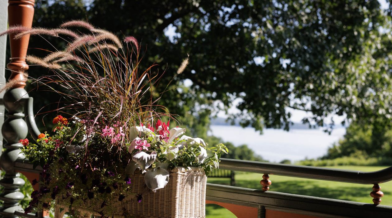 Flowers blooming on the back porch at Wilderstein Historic Site in Rhinebeck with the Hudson River in the background
