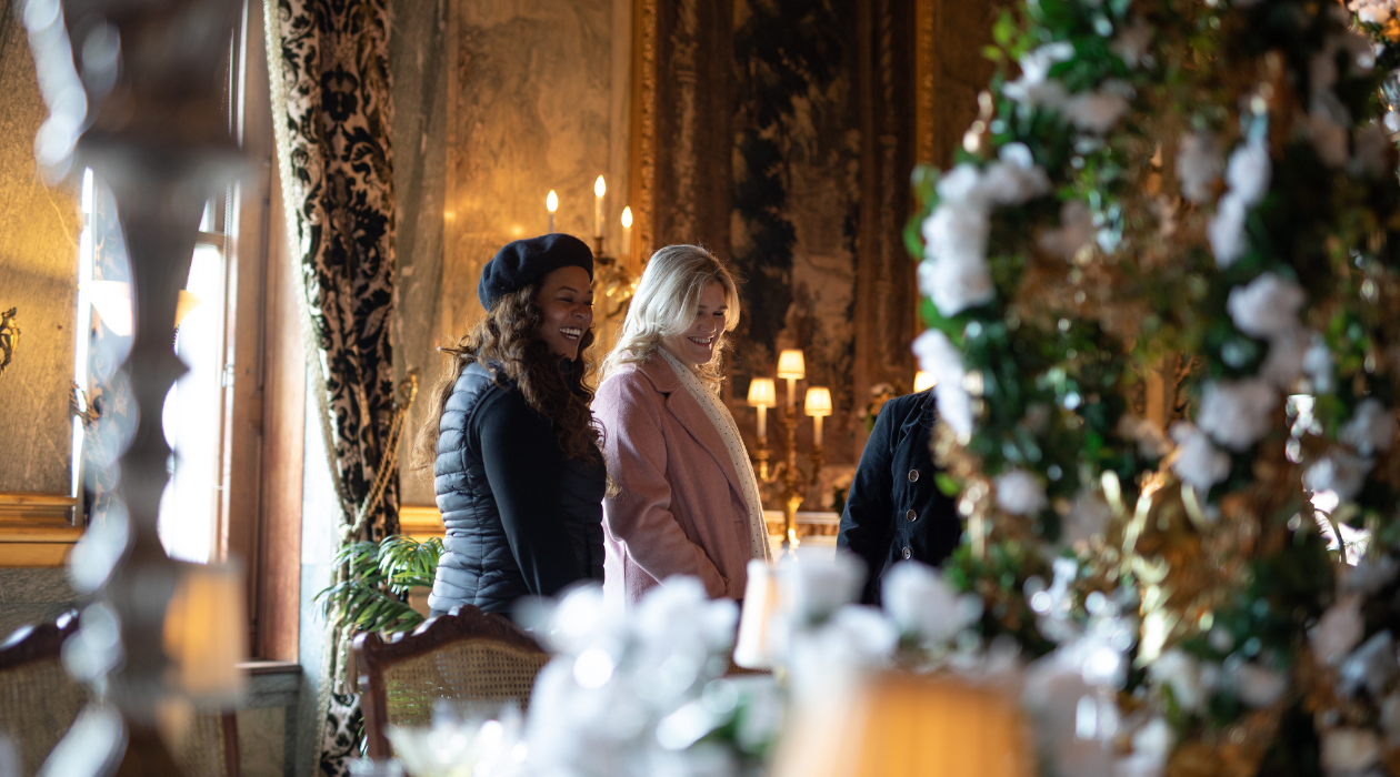 Two women look at the ornately decorated tablescapes in the grand parlor of Staatsburgh State Historic Site