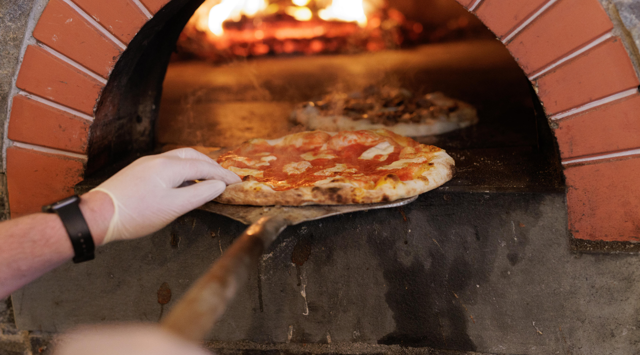 Pizza going into wood burning oven at Pizzeria Posto