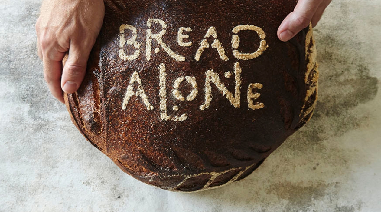 Bread Alone name stamped into a loaf of bread held by two hands