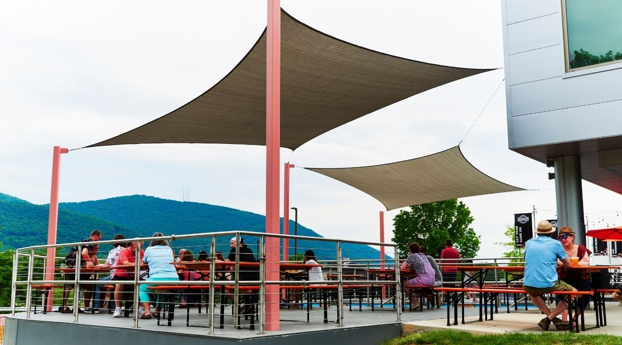 View of several people on a patio at tables under umbrellas; Industrial Arts Brewing in Beacon