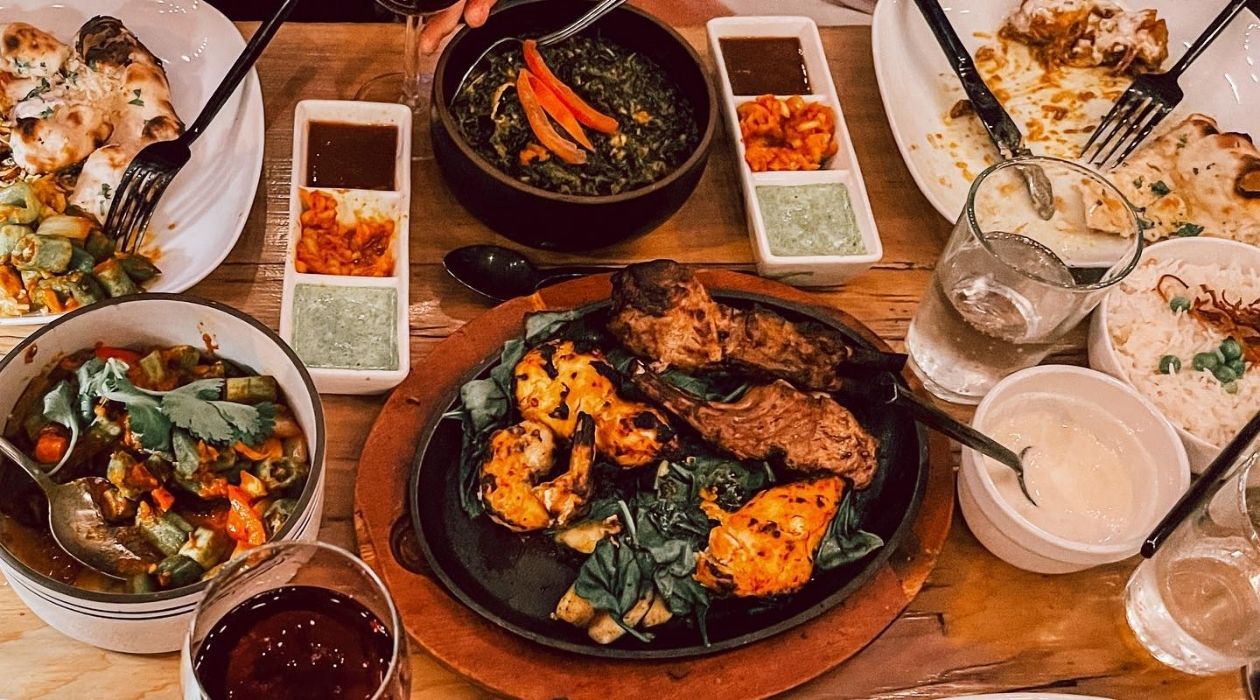 Table full of Indian dishes such as naan bread curry biryani rice and lamb
