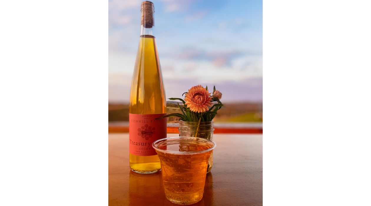 Bottle next to a glass of cider on a wooden bar