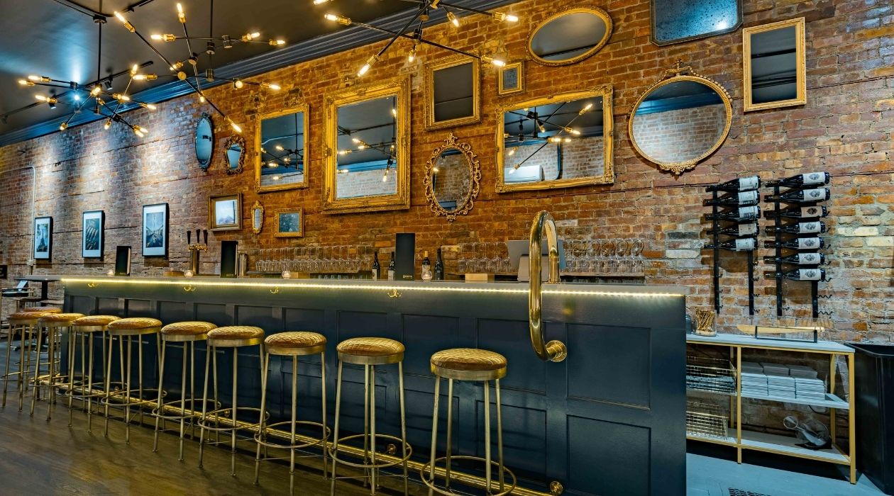 Dozens of mirrors on a brick wall behind a white marble bar